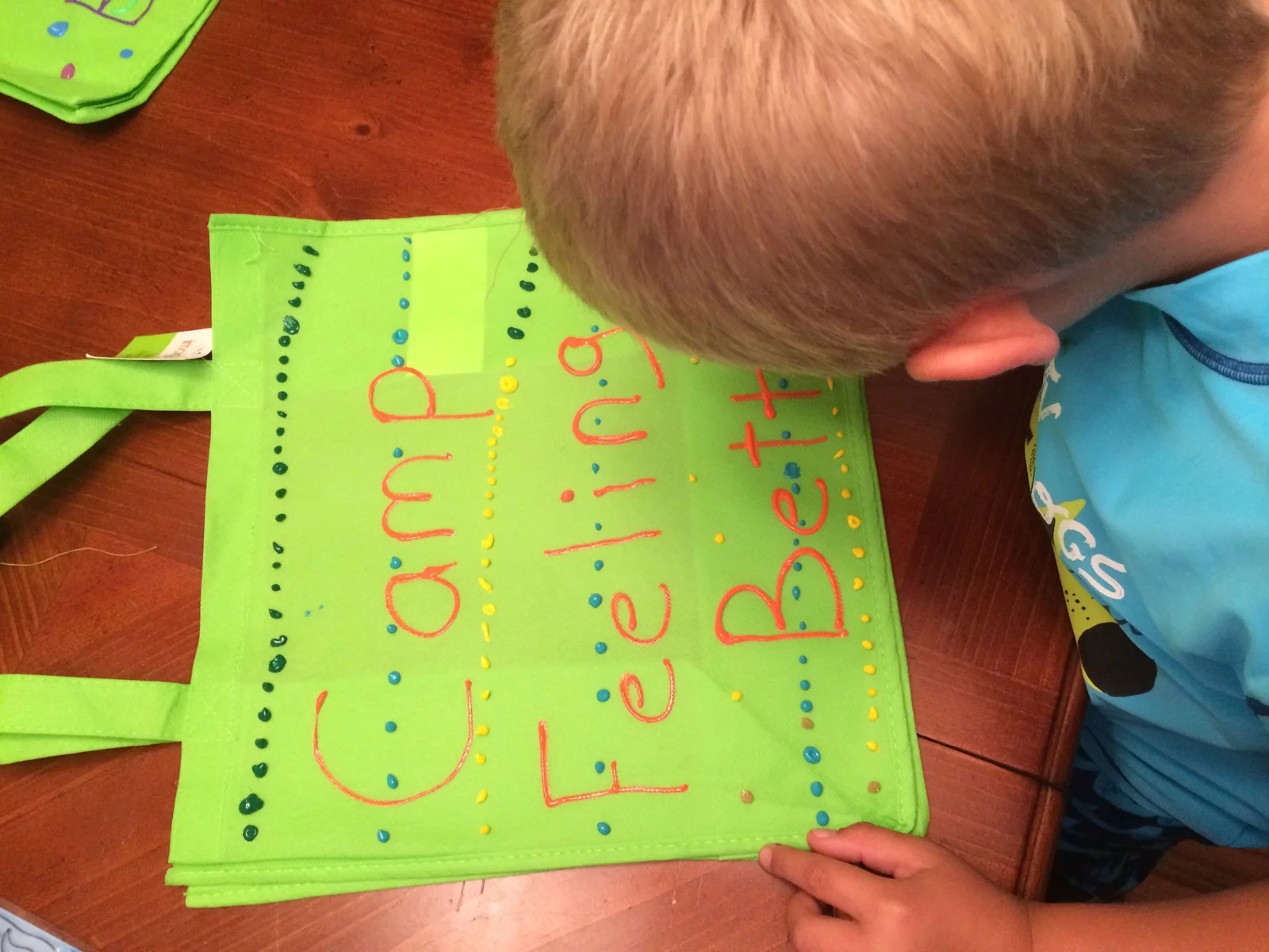 A child decorating a Camp Feeling Better tote bag