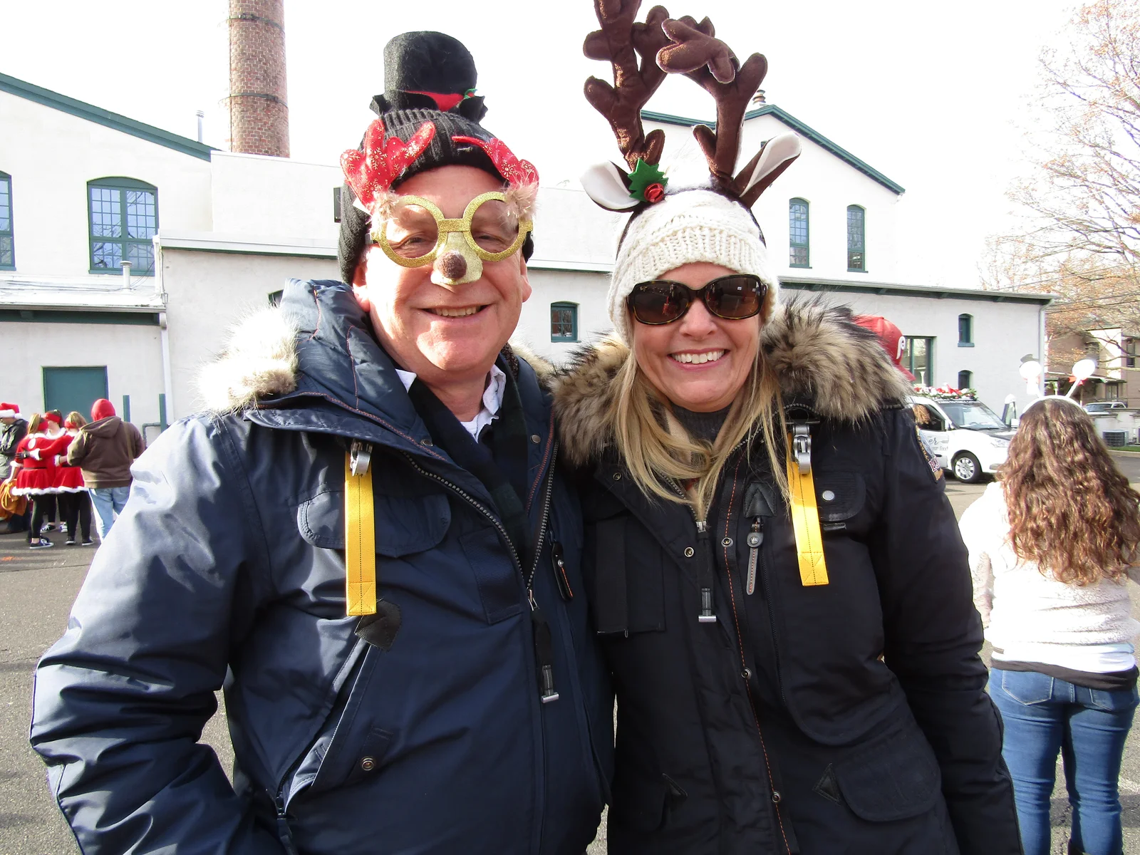 Two smiling supporters in festive hats at a Hands Holding Hearts event