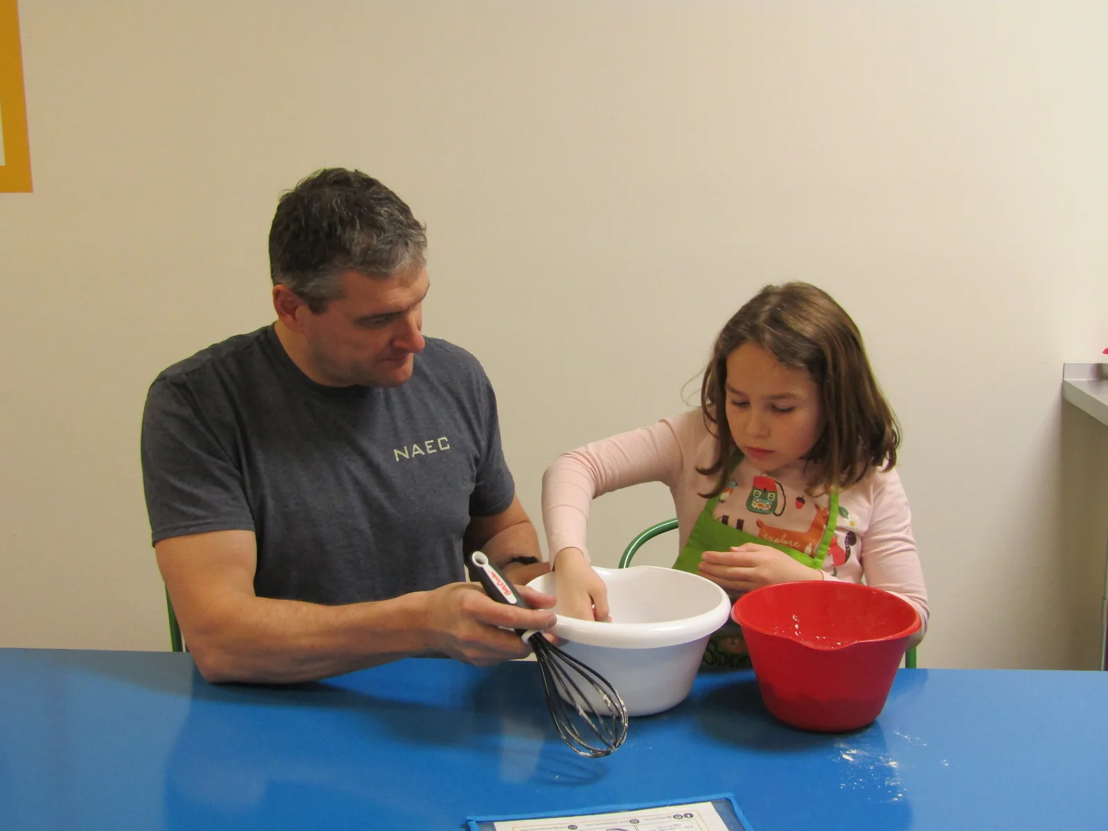 Children working on crafts at an outdoor camp table with volunteers