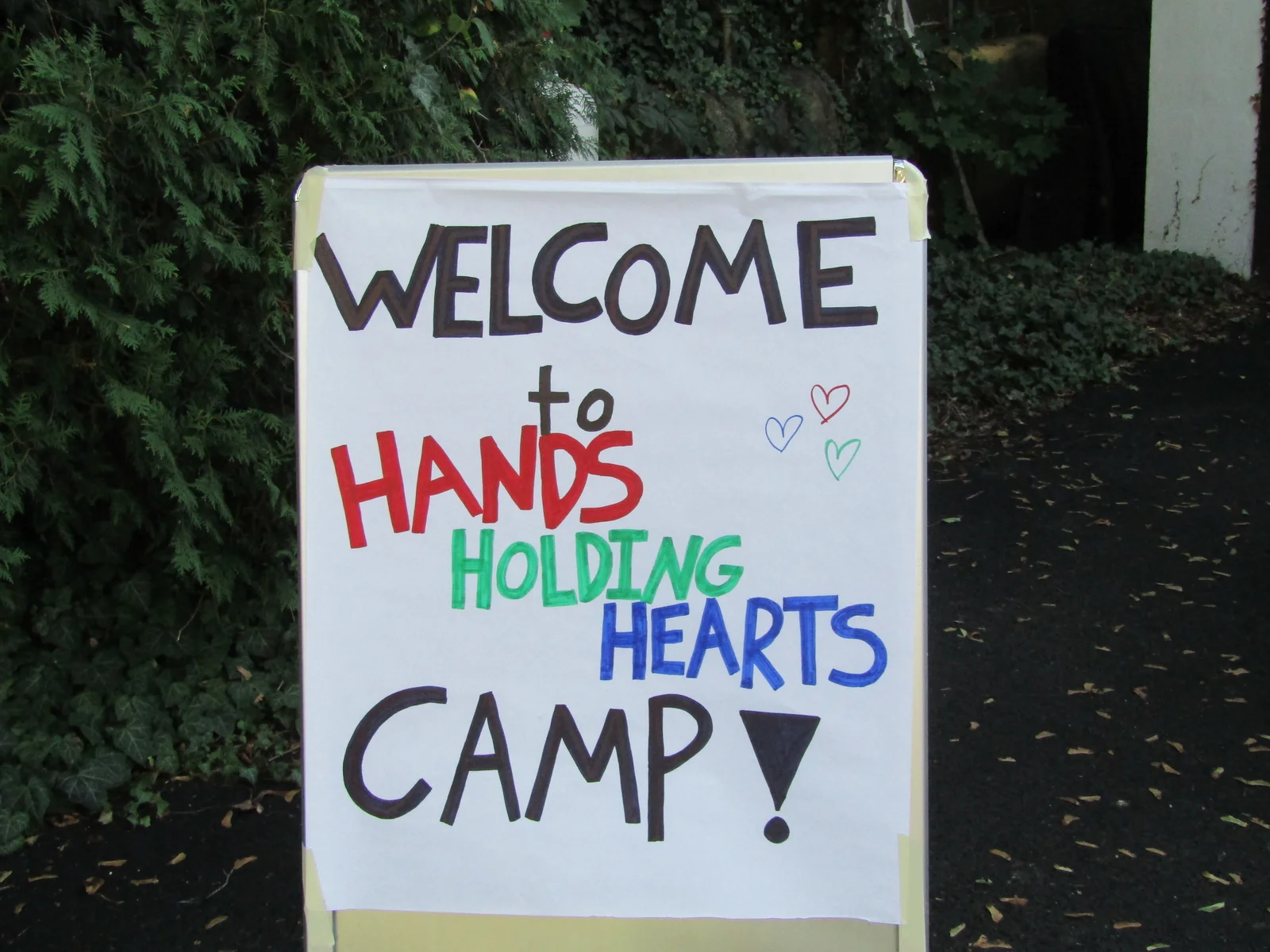 A hand-painted Welcome to Hands Holding Hearts Camp sign