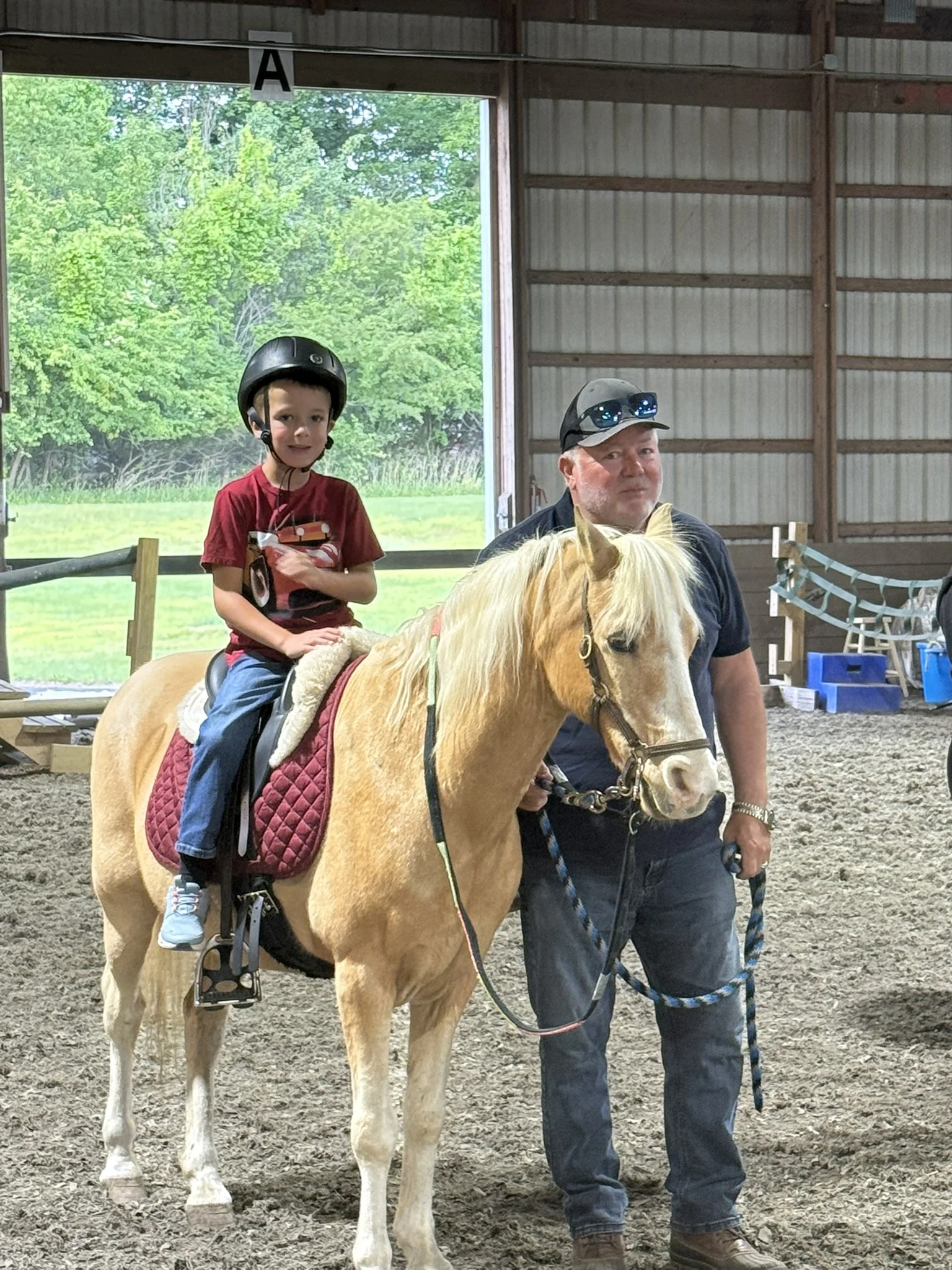 Child wearing a helmet riding a horse with an instructor at Special Equestrians
