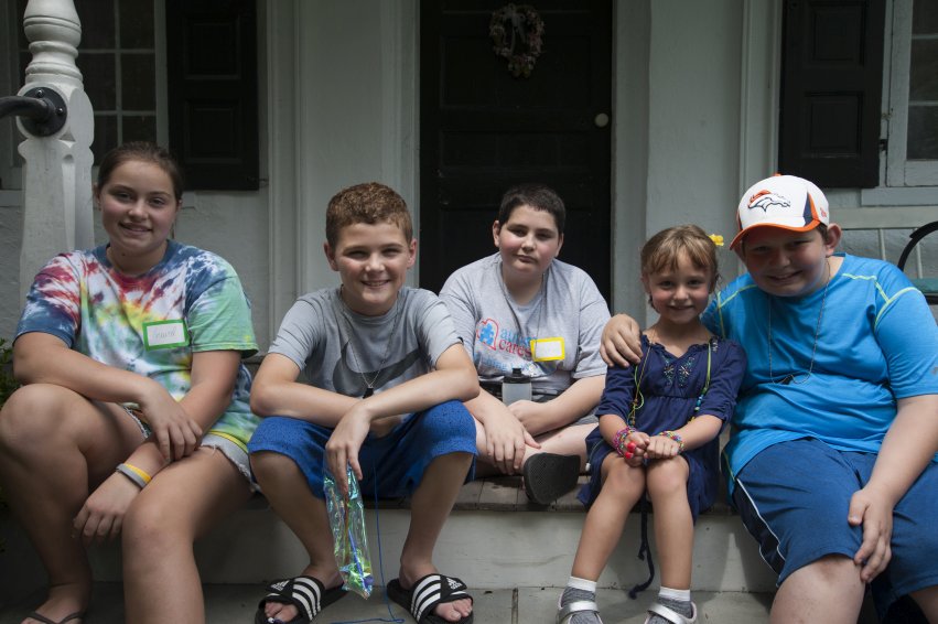 A group of children and teens smiling together at a Hands Holding Hearts program