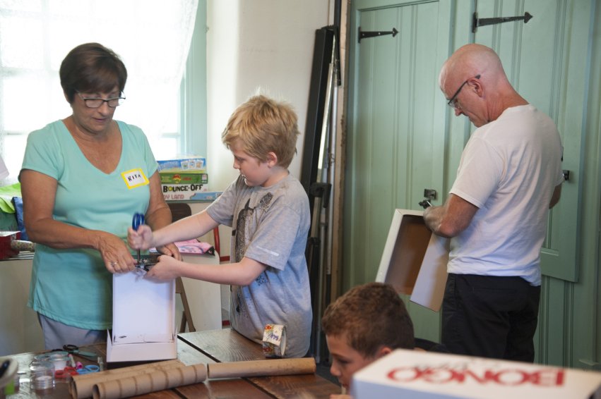 Children and a volunteer working on a craft project at a Hands Holding Hearts program