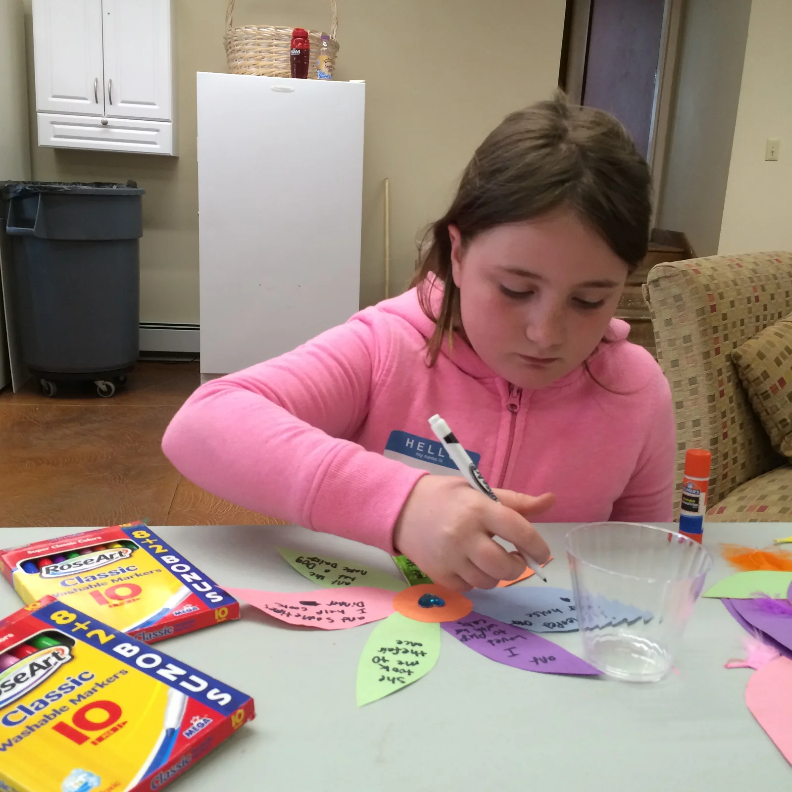 A girl painting at a camp craft table