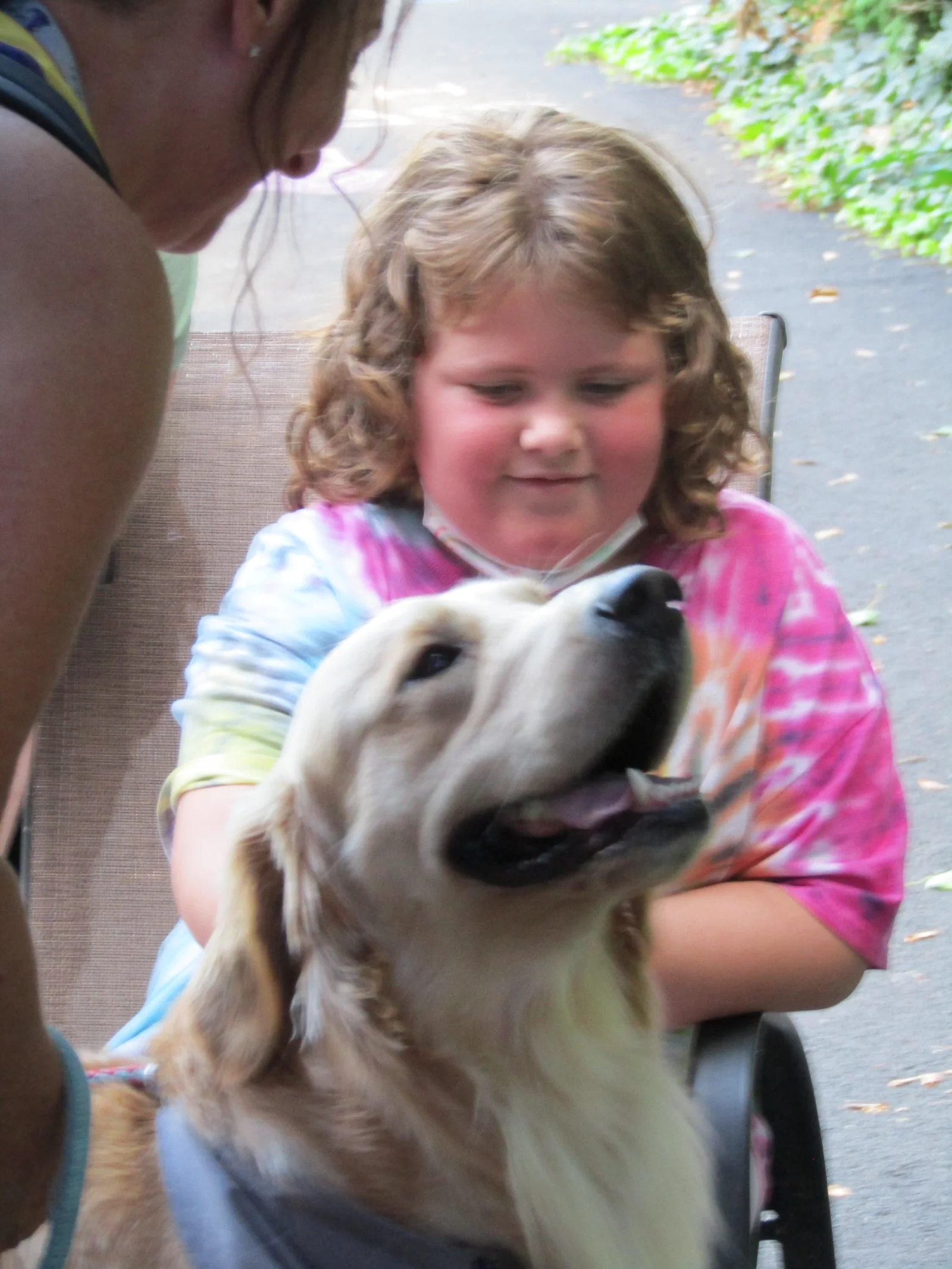 A smiling girl hugging a therapy dog at camp